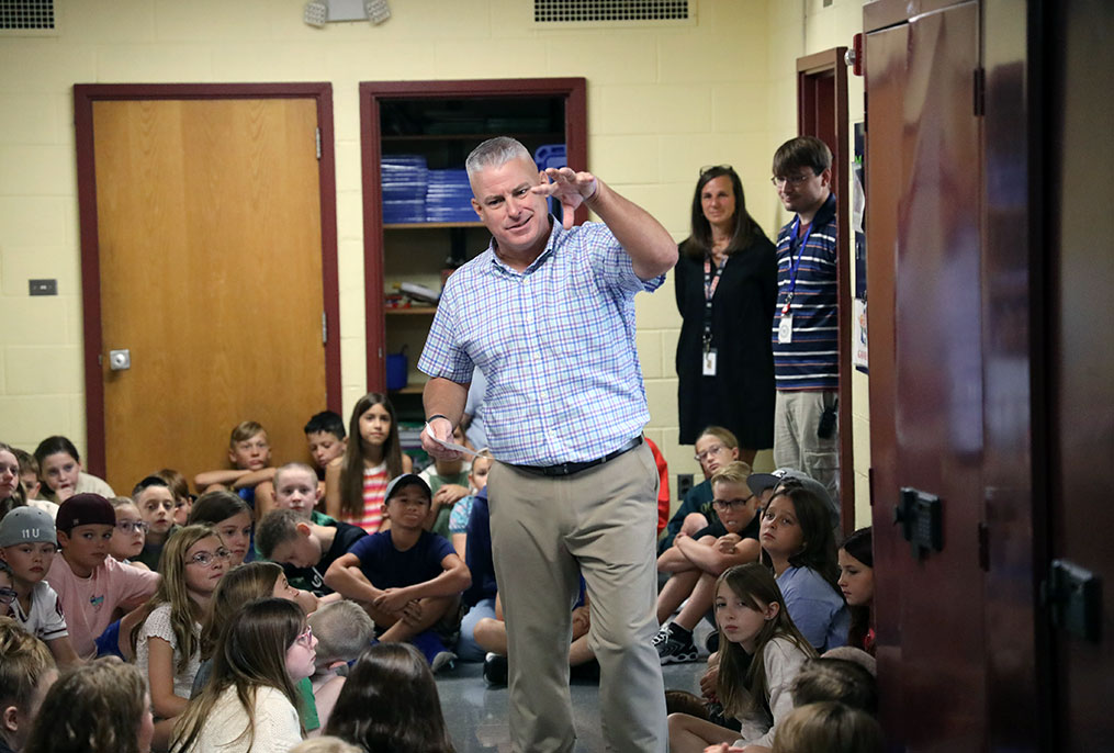 A teacher standing in a hallway with students.