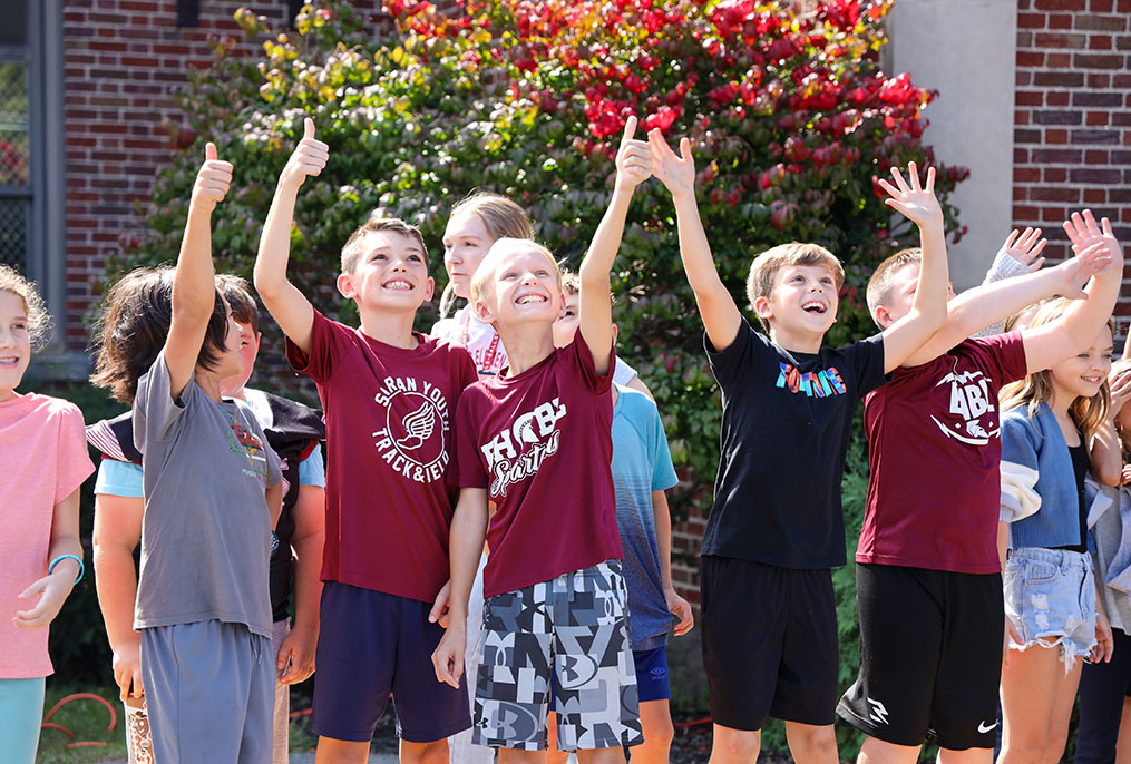 Students waving and giving thumbs up.