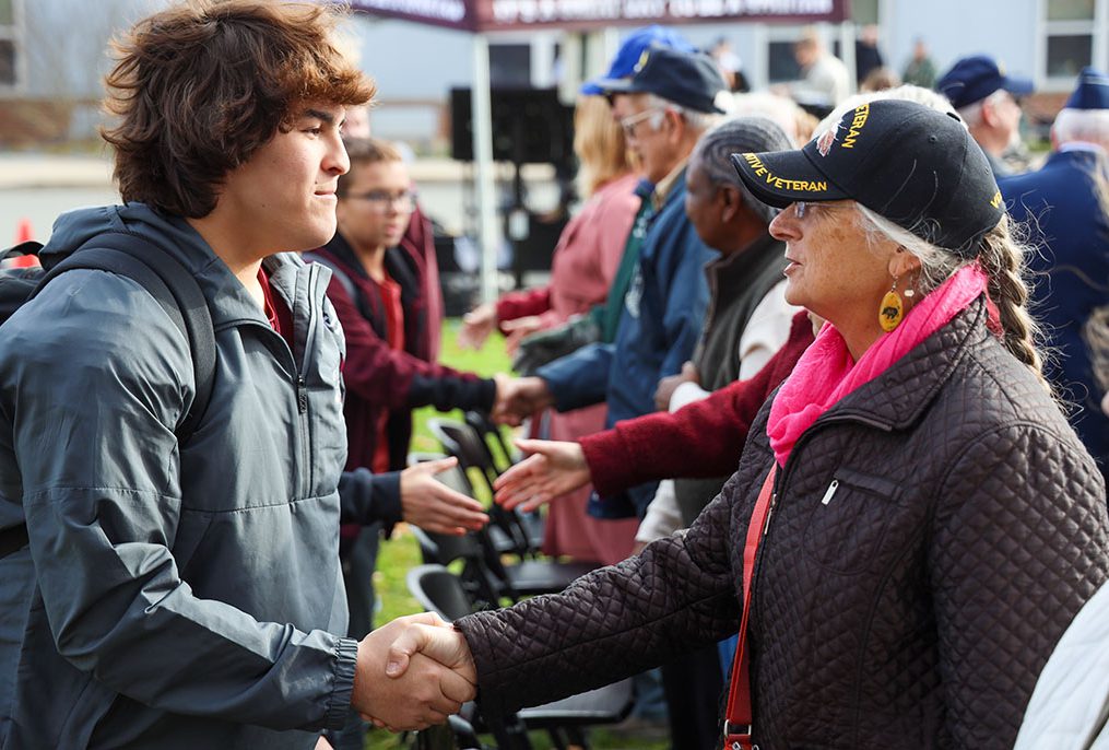 High school student shakes hands with veteran