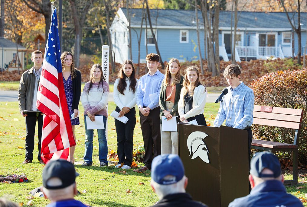 High school students speak to local veterans outside